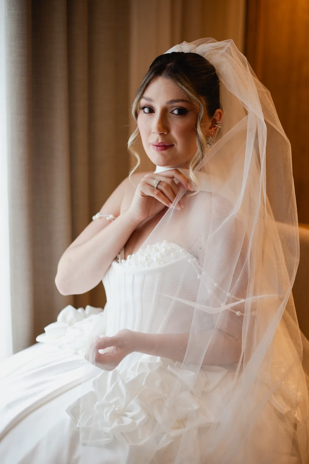 Noiva de véu com vestido de corpete drapeado, no dia do casamento