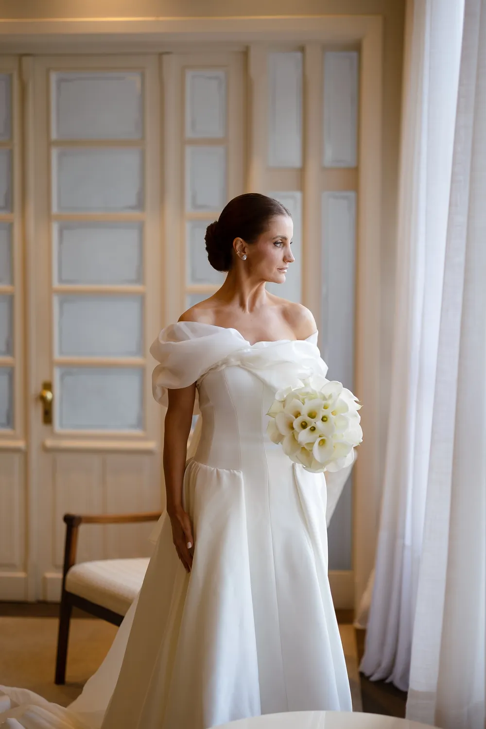 Noiva com vestido de organza e mangas volumosas, segurando buquê de copos-de-leite